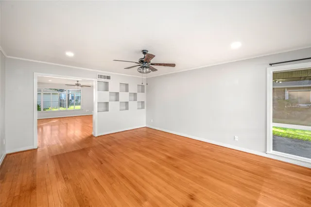 a view of empty room with wooden floor and fan