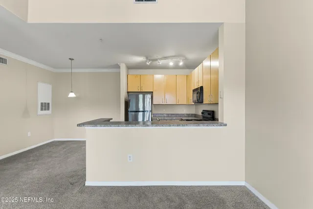 a large kitchen with stainless steel appliances a large counter top