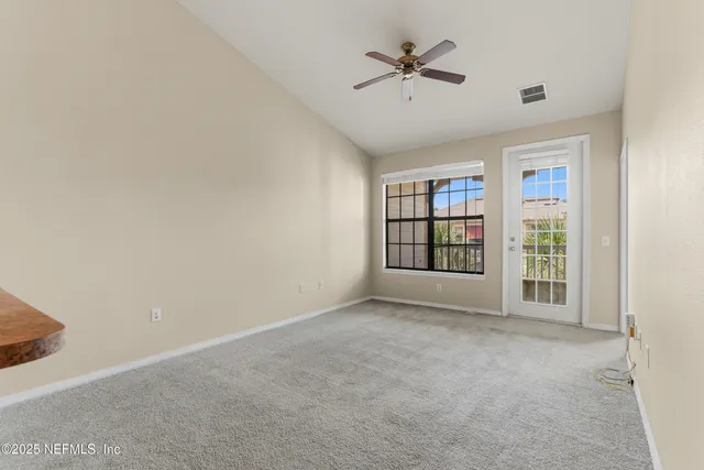 a view of an empty room with a window and a ceiling fan