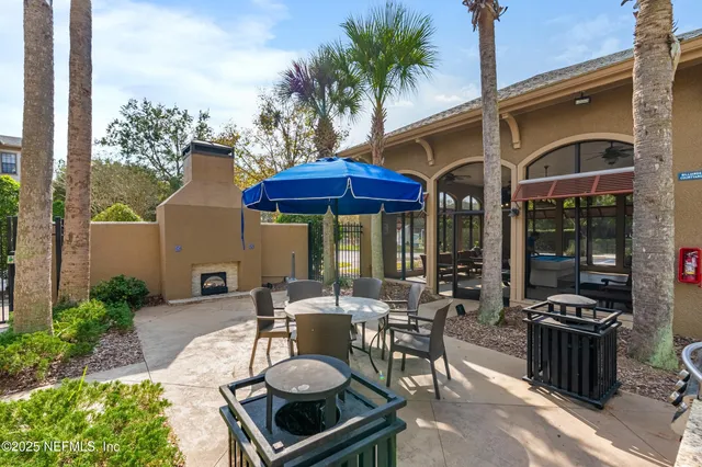 a view of a patio with table and chairs potted plants and floor to ceiling window