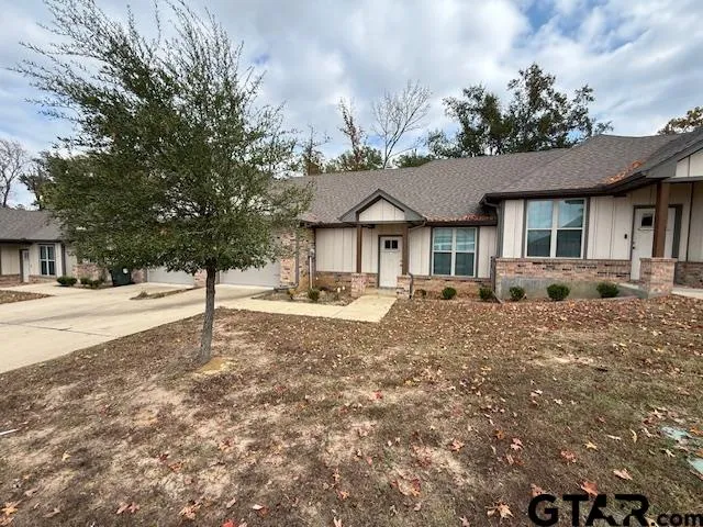 a front view of a house with a yard and large tree