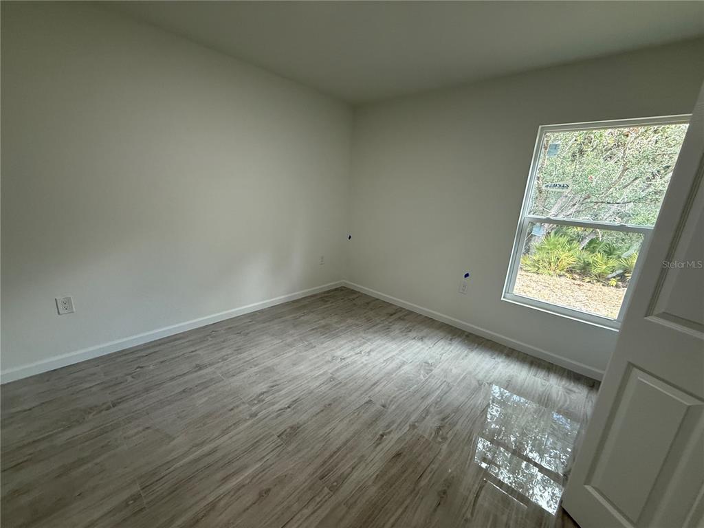 5358 Rhapsody Avenue North Port, FL 34288 - Photo 19 of 28 an empty room with wooden floor and windows