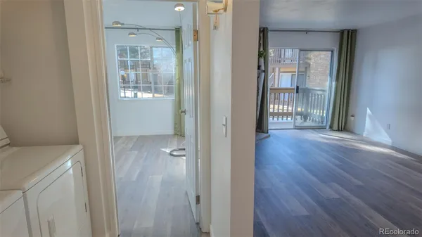 a view of a hallway with wooden floor and a bathroom