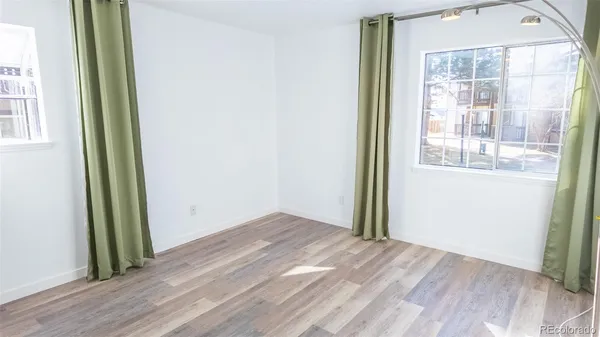 an empty room with wooden floor and windows