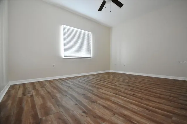 a view of an empty room with wooden floor and a bathroom