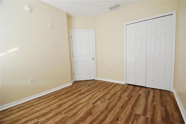 a view of an empty room with wooden floor and a bathroom