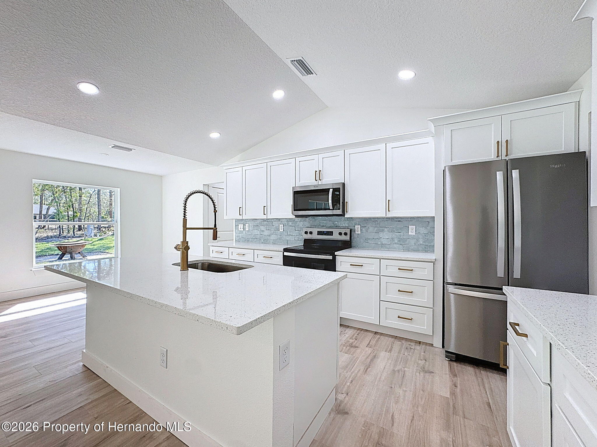8988 Waterbird Way Weeki Wachee, FL 34613 - Photo 13 of 42 a kitchen with refrigerator cabinets and wooden floor