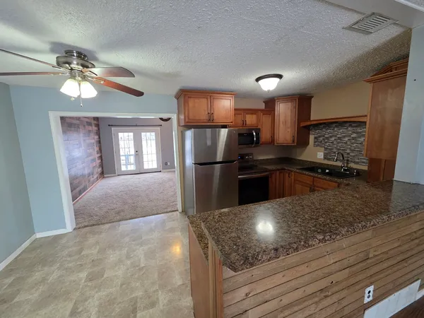 a kitchen with granite countertop a refrigerator and microwave