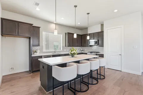 a kitchen with stainless steel appliances granite countertop a sink a stove a refrigerator and island with wooden floor