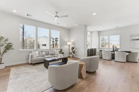 a living room with furniture kitchen view and a large window
