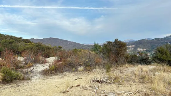 a view of a dry yard with mountains in the background
