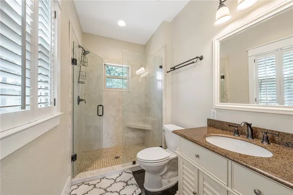 a bathroom with a granite countertop sink toilet and shower