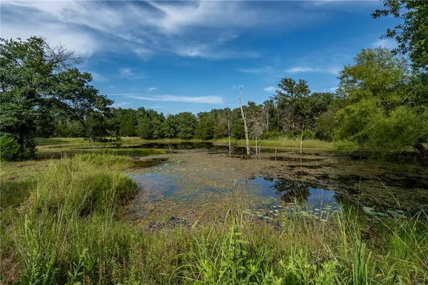 a view of a lake with table and chairs next to yard