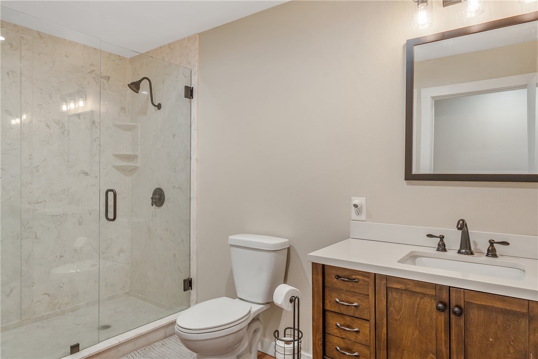 2033 Lcr 704, Unit COUNTYROAD Kosse, TX 76653 - Photo 28 of 31 a bathroom with a granite countertop toilet a sink a mirror and shower