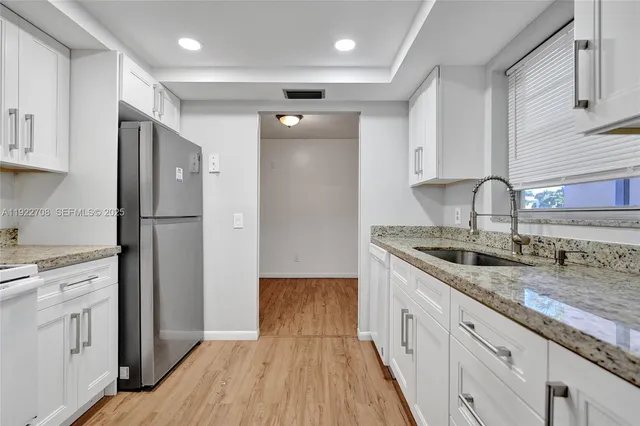 a kitchen with a sink a refrigerator and cabinets