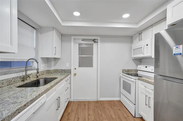 a kitchen with a refrigerator stove and white cabinets