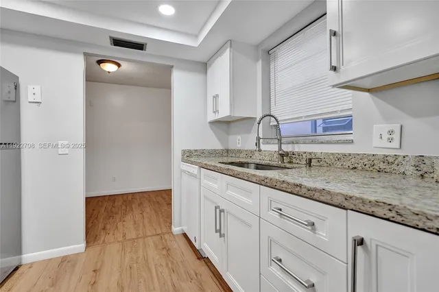 a kitchen with granite countertop a sink and cabinets