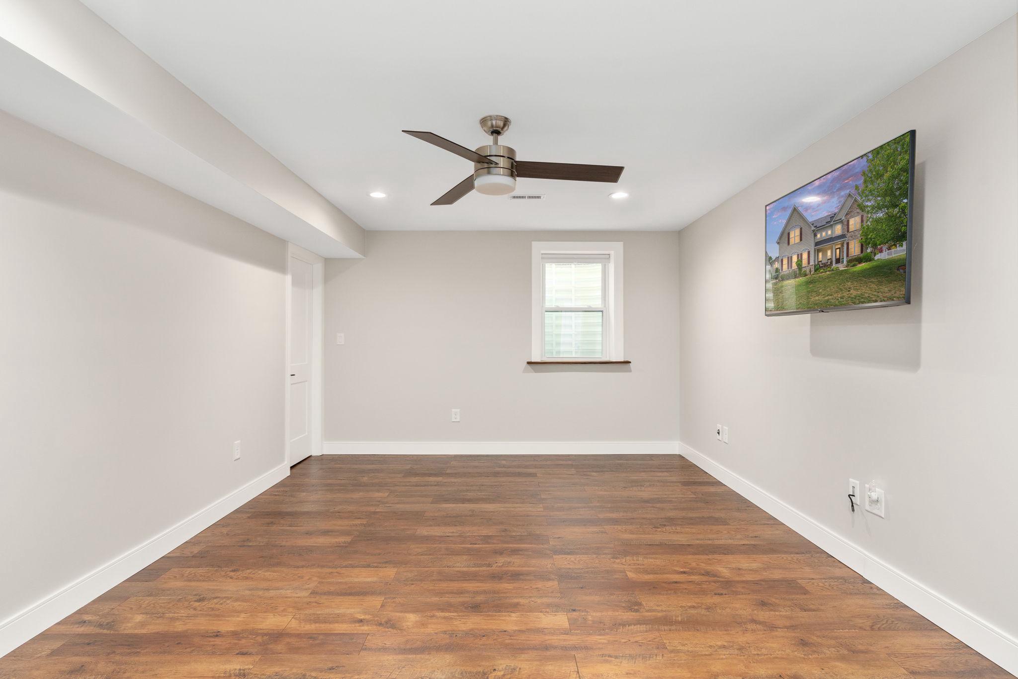 9417 Reservoir Road Fredericksburg, VA 22407 - Photo 39 of 76 an empty room with wooden floor ceiling fan and windows