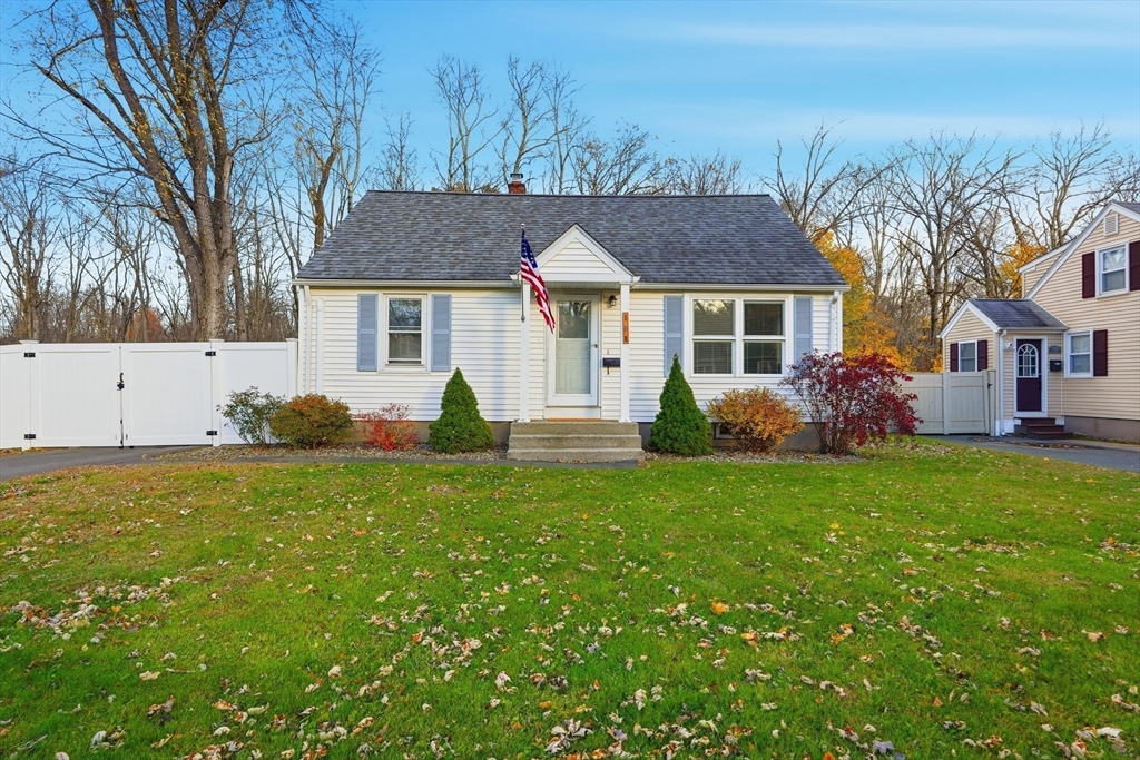 a front view of house with yard and trees in the background