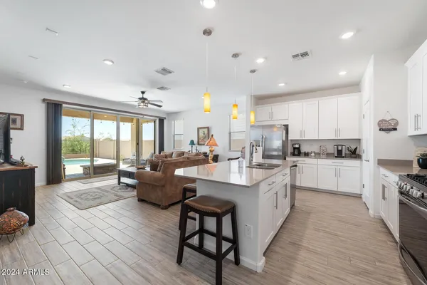a large white kitchen with kitchen island a large counter top space a sink stainless steel appliances and cabinets
