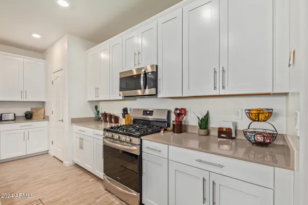a kitchen with stainless steel appliances granite countertop a sink a stove a microwave a refrigerator a sink and white cabinets