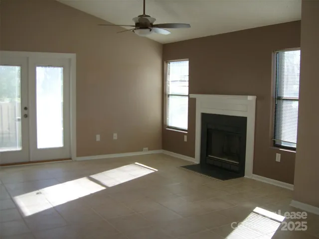 an empty room with windows and fireplace
