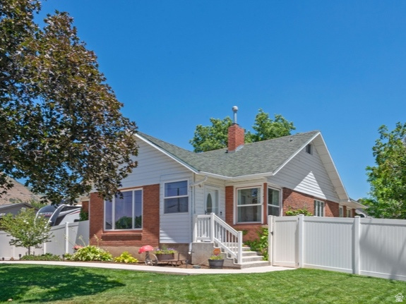1214 North 300 West Mapleton, UT 84664 - Photo 1 of 33 Traditional-style residence featuring a brick and white siding exterior, a prominent front lawn, a newer white vinyl fence, a covered porch, and mature landscaping on a large corner lot