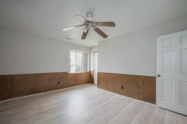 an empty room with wooden floor cabinet and windows