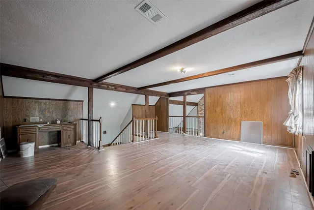 a view of an empty room with wooden floor and windows