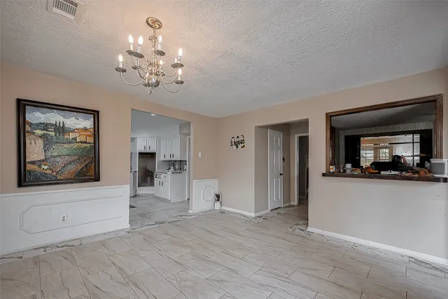 a view of a room with a chandelier and wooden floor