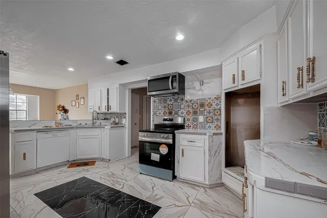 a kitchen with stainless steel appliances granite countertop a refrigerator stove top oven and sink