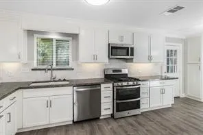 a kitchen with granite countertop white cabinets and stainless steel appliances