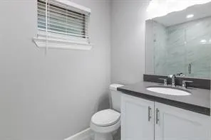 a bathroom with a granite countertop toilet sink and mirror