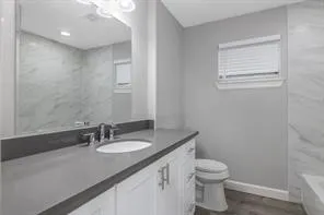 a bathroom with a granite countertop sink toilet and a mirror