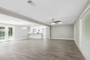 an empty room with wooden floor chandelier fan and windows