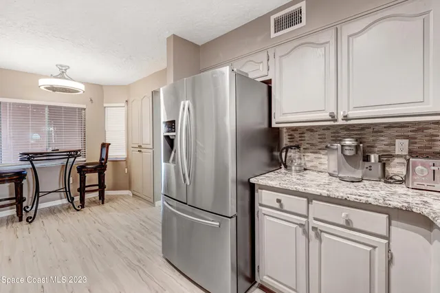 a kitchen with stainless steel appliances granite countertop a refrigerator a sink and white cabinets