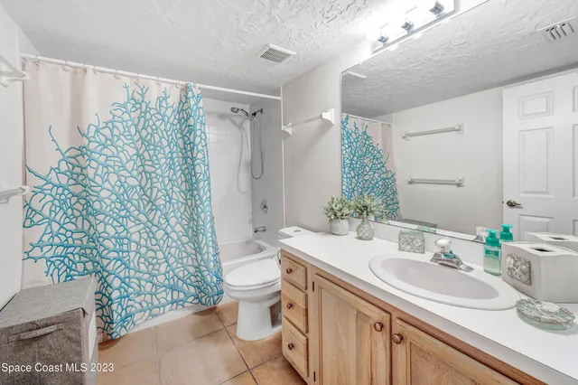 a bathroom with a granite countertop sink a toilet and shower curtain