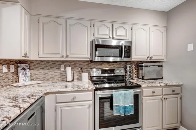 a kitchen with granite countertop white cabinets and stainless steel appliances