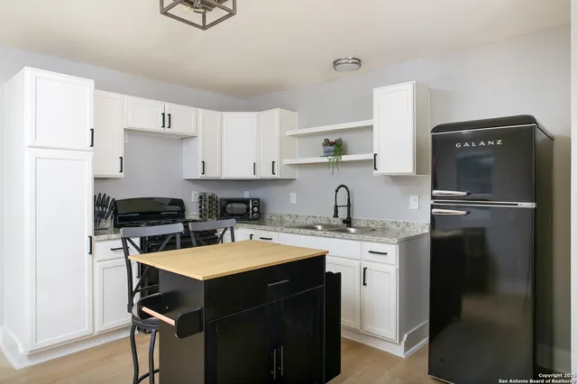 a kitchen with granite countertop a stove a sink and a microwave