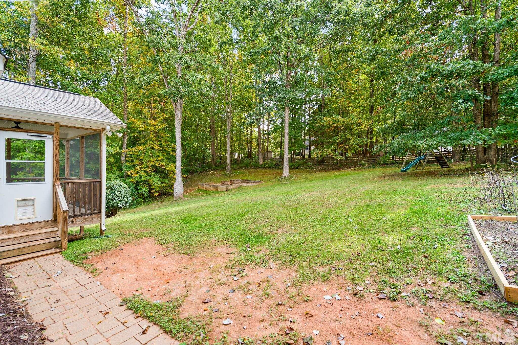 130 Broken Lance Drive Youngsville, NC 27596 - Photo 17 of 32 a backyard of a house with plants and large tree