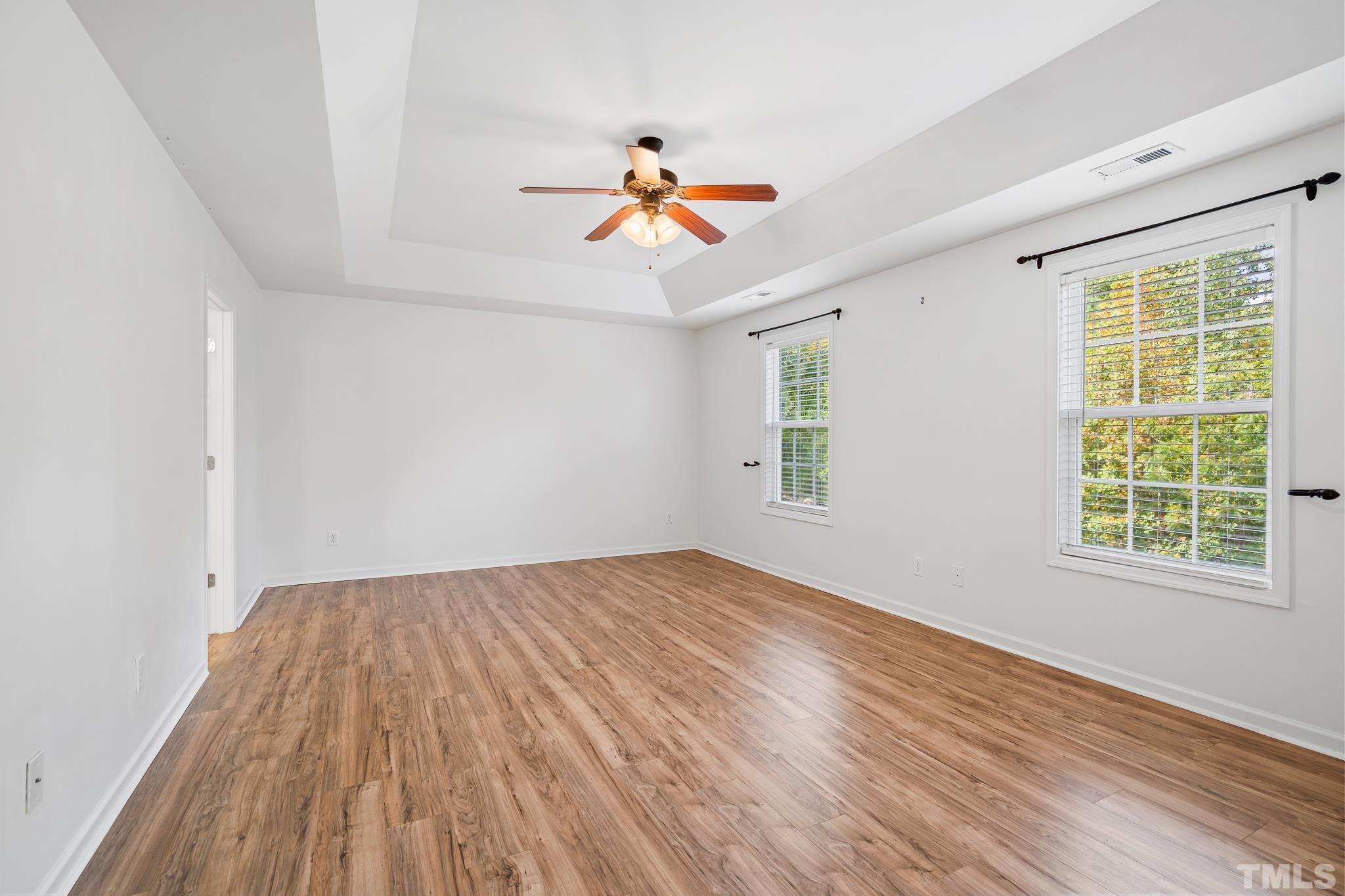 130 Broken Lance Drive Youngsville, NC 27596 - Photo 25 of 32 an empty room with wooden floor ceiling fan and windows