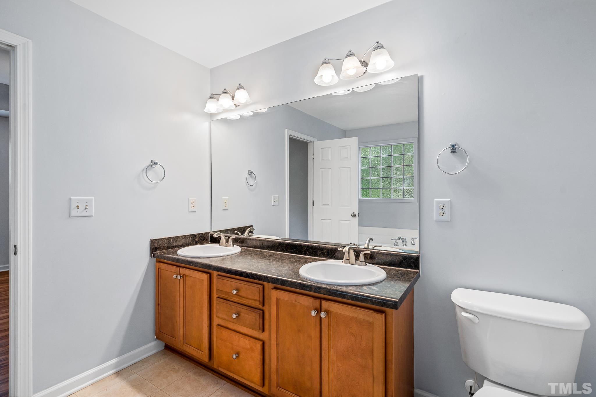 130 Broken Lance Drive Youngsville, NC 27596 - Photo 28 of 32 a bathroom with a granite countertop sink a toilet and a mirror