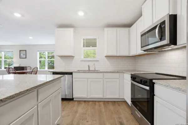 a kitchen with stainless steel appliances granite countertop white cabinets granite counter tops and a window