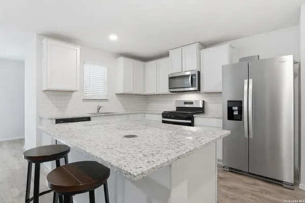 a kitchen with a refrigerator a stove a sink and a granite counter tops