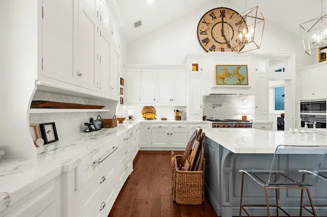 a large kitchen with a stove a kitchen island a dining table and chairs with wooden floor