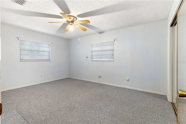 an empty room with windows and fan