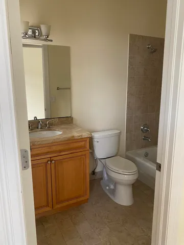 a bathroom with a granite countertop toilet a sink and a mirror
