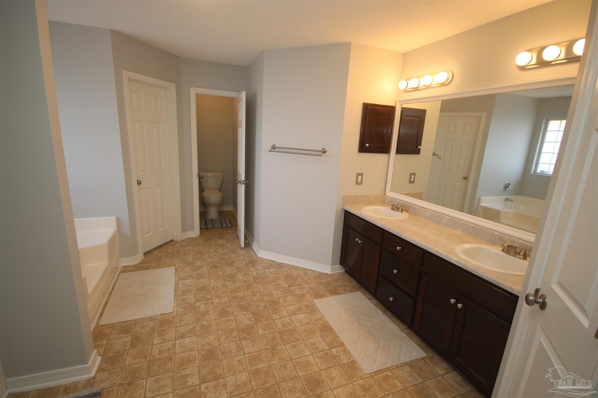 4930 Chads Circle Milton, FL 32571 - Photo 29 of 50 a spacious bathroom with a double vanity sink a large mirror and a shower