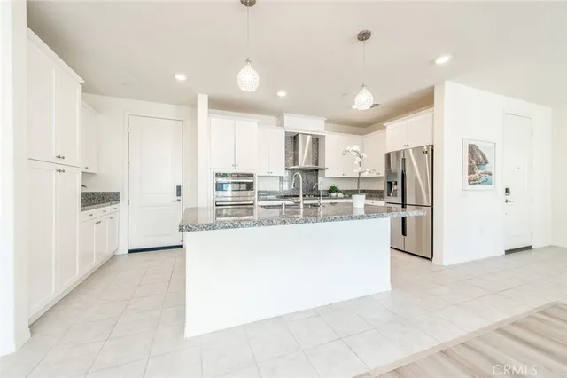 a large kitchen with kitchen island a refrigerator a oven a sink and white cabinets