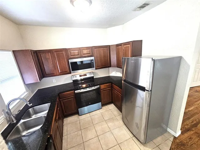 a kitchen with stainless steel appliances a refrigerator and a stove top oven